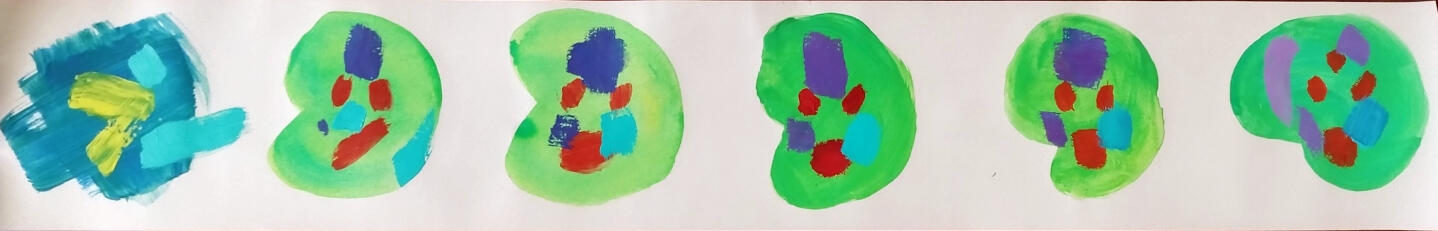 A photo of a roll of wallpaper. The wallpaper roll is opened and the inside has been painted with green blobs. Inside the blobs are abstract and colorful shapes.